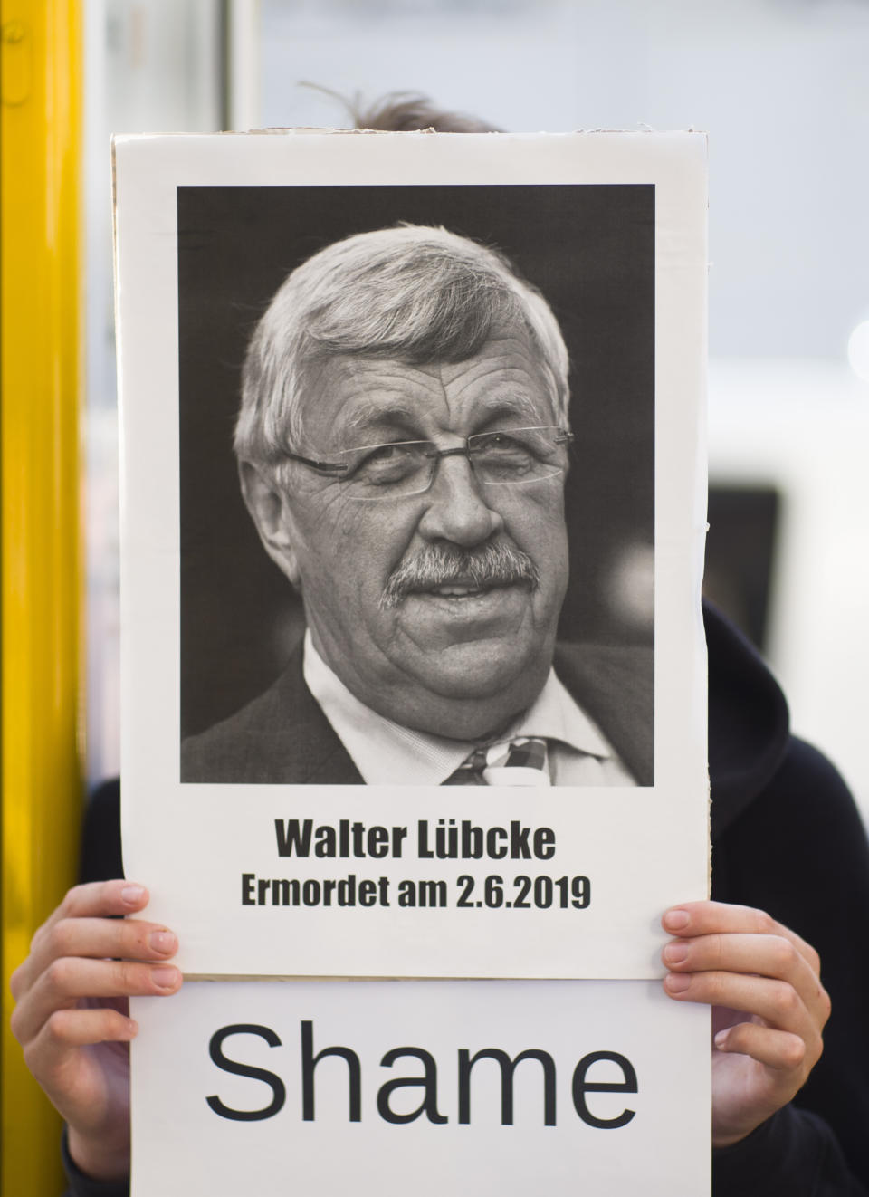 FILE - In this June 18, 2019 file photo, an activists of the Antifa, anti-fascism action, shows a poster of Walter Luebcke during a protest against right-wing violence in Berlin, Germany, Tuesday, June 18, 2019. Germany's top security official says the far-right extremist suspected in the killing of a politician from Chancellor Angela Merkel's party has told authorities that he acted alone. Walter Luebcke, who led the Kassel regional administration in central Germany, was fatally shot in the head at his home on June 2. (AP Photo/Markus Schreiber)