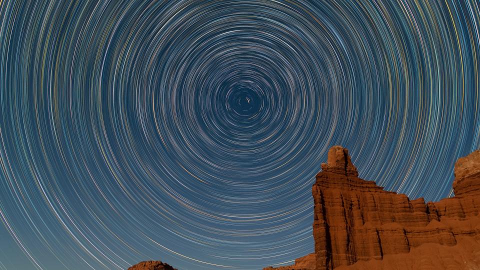 rock formation in lower right corner of the image with star trails above.