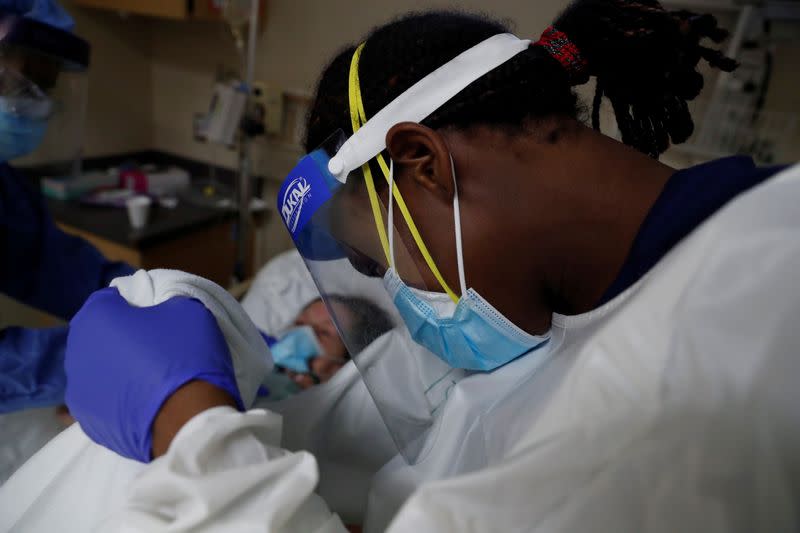 Patient Care Technician Fanta Keita treats Donna Plummer, a coronavirus disease (COVID-19) positive patient, as she lays on the emergency room bed at Roseland Community Hospital on the South Side of Chicago, Illinois