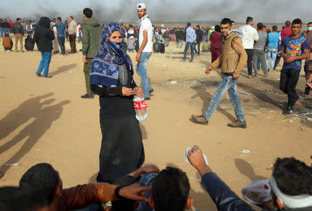 Palestinian Taheyah Qdeih provides the demonstrators with water during a protest at the Israel-Gaza border, in the southern Gaza Strip April 13, 2018. REUTERS/Samar Abo Elouf