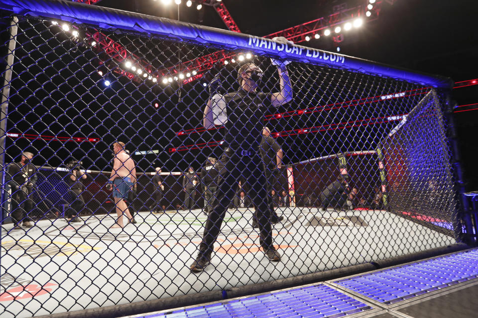 A worker wipes down the octagon between bouts during the UFC 249 mixed martial art event, Saturday, May 9, 2020, in Jacksonville, Fla. (AP Photo/John Raoux)