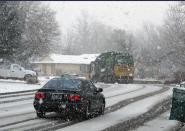 Snowflakes fall as a car follows a garbage truck down a residential street in Sparks, Nev., Friday, Jan. 20, 2017. The Reno-Sparks area is expected to get up to eight inches of snow through the weekend. As much as another six feet of new snow is possible in the upper elevations of the Sierra Nevada, where a winter storm warning continues into Monday. (AP Photo/Scott Sonner)