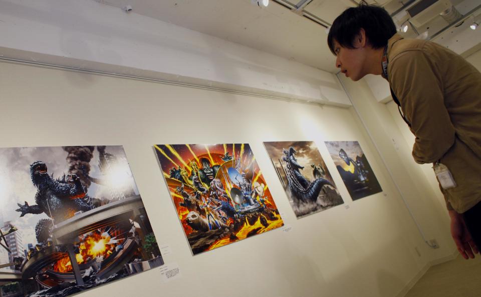 In this Monday, April 28, 2014 photo, a visitor looks at art work by Yuji Kaida of Godzilla, at Cheepa's Cafe gallery in Tokyo. Will the Hollywood Godzilla be a tribute or an embarrassment for Japan’s monstrous legacy? That’s the big question on the minds of fans here ahead of the film’s May 16 opening. (AP Photo/Junji Kurokawa)