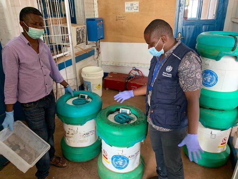 Workers from the World Health Organization (WHO) inspect an Arktek ultra-cold vaccine storage cylinder containing Ebola vaccines in Mbandaka