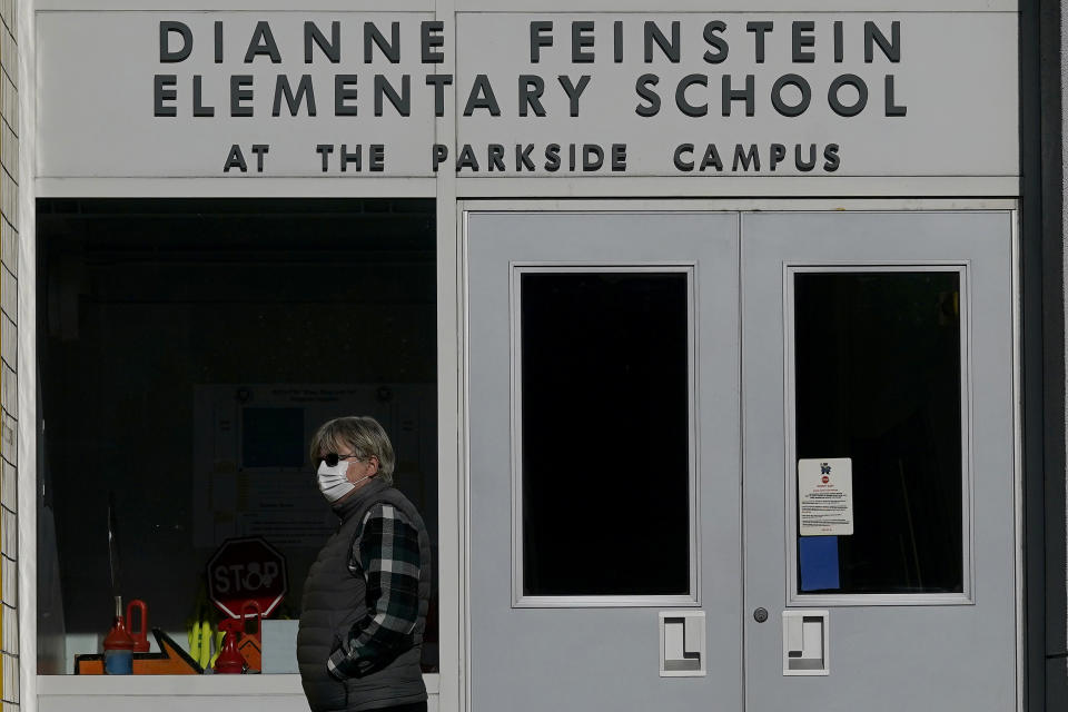 FILE - A pedestrian walks below a sign for Dianne Feinstein Elementary School in San Francisco on Dec. 17, 2020. In a city with the lowest percentage of children of all major American cities, school board elections in San Francisco have often been an afterthought. One of the first issues to garner national attention was the board's decision to rename 44 of the city's public schools they said honored public figures linked to racism, sexism and injustice. On the list were names like George Washington, Abraham Lincoln and trailblazing California Sen. Dianne Feinstein.(AP Photo/Jeff Chiu, File)