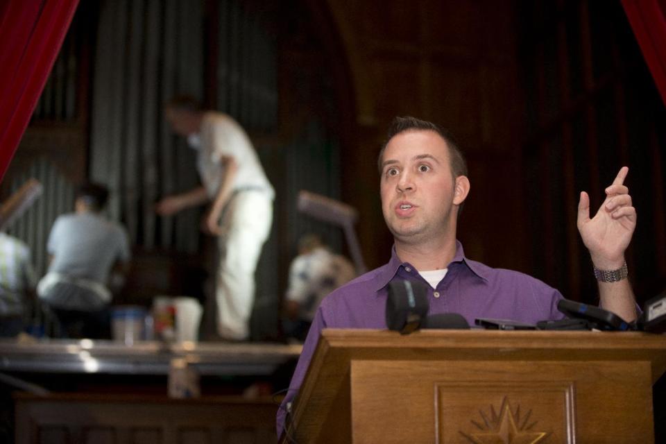 As Richard Weinberg, director of communications at Washington National Cathedral, answers media questions, William Adair of Gold Leaf Studios works in the background with his staff to remove green paint from the organ in the Washington National Cathedral's historic Bethlehem Chapel, Tuesday, July 30, 2013, in Washington. Officials at the cathedral discovered the paint inside two chapels Monday afternoon. The paint was splashed onto the organ and on the floor inside the Bethlehem Chapel on the basement level and inside Children's Chapel in the nave of the cathedral. (AP Photo/Carolyn Kaster)