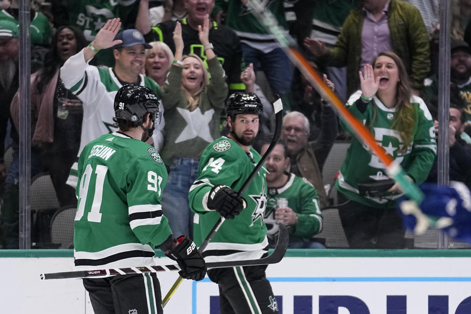 Dallas Stars center Tyler Seguin (91) and left wing Jamie Benn (14) celebrate after Benn scored in the first period of an NHL hockey game against the Vancouver Canucks, Monday, Feb. 27, 2023, in Dallas. (AP Photo/Tony Gutierrez)