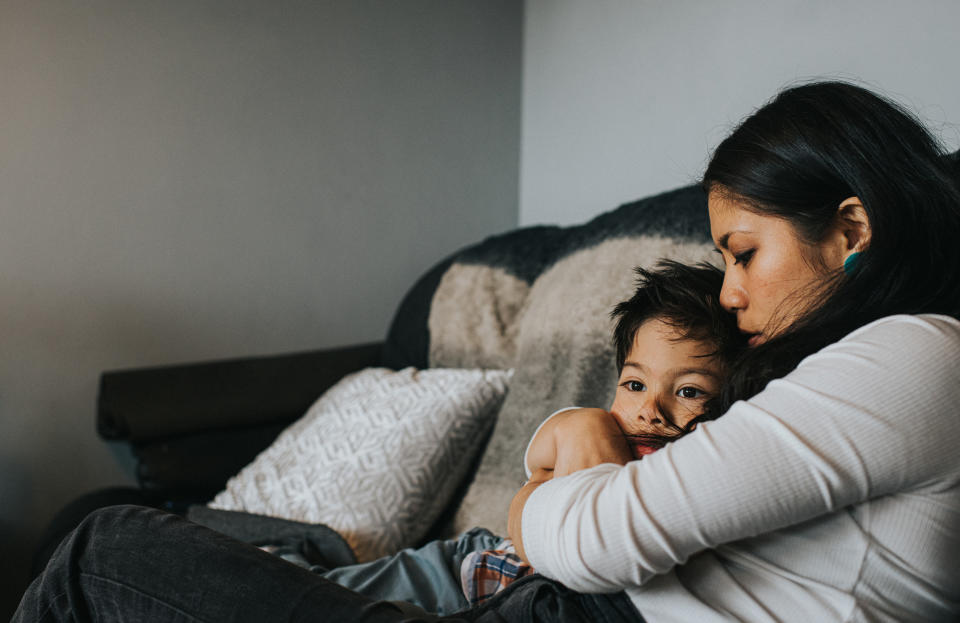 A woman cuddling her child on a couch