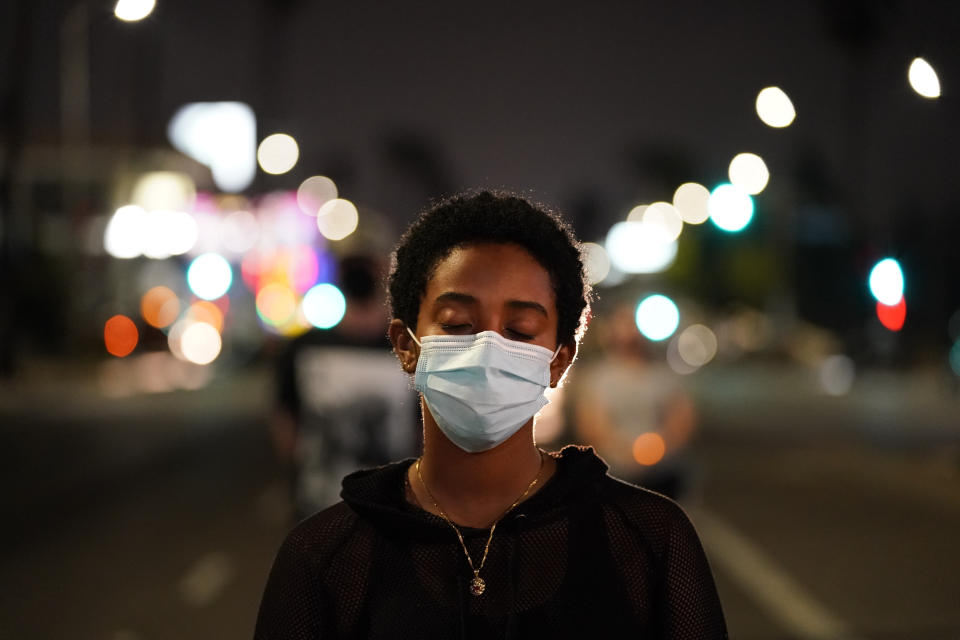 Léoh Hailu-Ghermay listens to a song with her eyes closed during a candlelight vigil for Elijah McClain in Los Angeles, Aug. 24, 2020. McClain died in 2019 after he was stopped while walking to his apartment by three Aurora, Colo., police officers. A trial for two of the officers charged for Elijah McClain's death is set to begin Friday, Sept. 15, 2023 with jury selection. (AP Photo/Jae C. Hong, file)