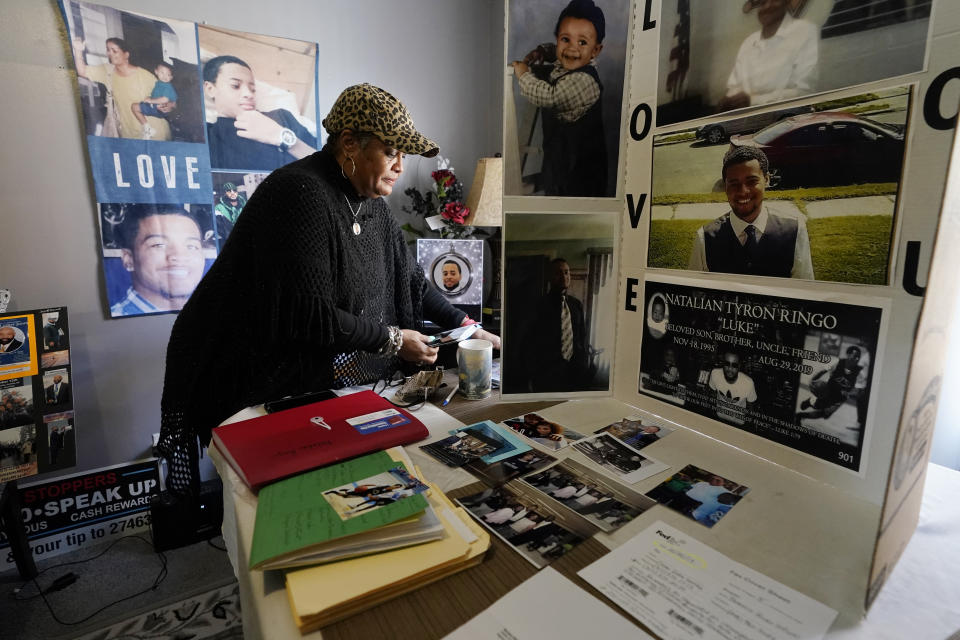 Bernice Ringo looks through photographs of her son Natalian, on Tuesday, March 28, 2023, in Detroit. Ringo had hoped to move him from Detroit and away from the crime she had feared most of his life, but those plans crumbled when Natalian was fatally shot in 2019. The victim compensation program ultimately denied Ringo's application because they said her son had contributed to his murder. (AP Photo/Carlos Osorio)