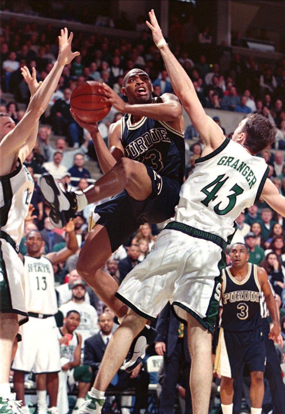 Purdue's Mike Robinson (23)  goes up for two points against Michigan State's A. J. Granger (43) and Jason Klein left  during the first half of play at the Breslin Arena in East Lansing Mich. Sunday March 1 1998. The Spartans lost to the Boilermakers in overtime 99-96.