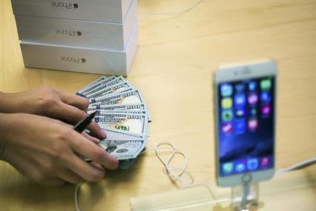 An employee counts money while selling new iPhone 6 phones at the Fifth Avenue Apple store on the first day of sales in Manhattan, New York September 19, 2014. REUTERS/Adrees Latif