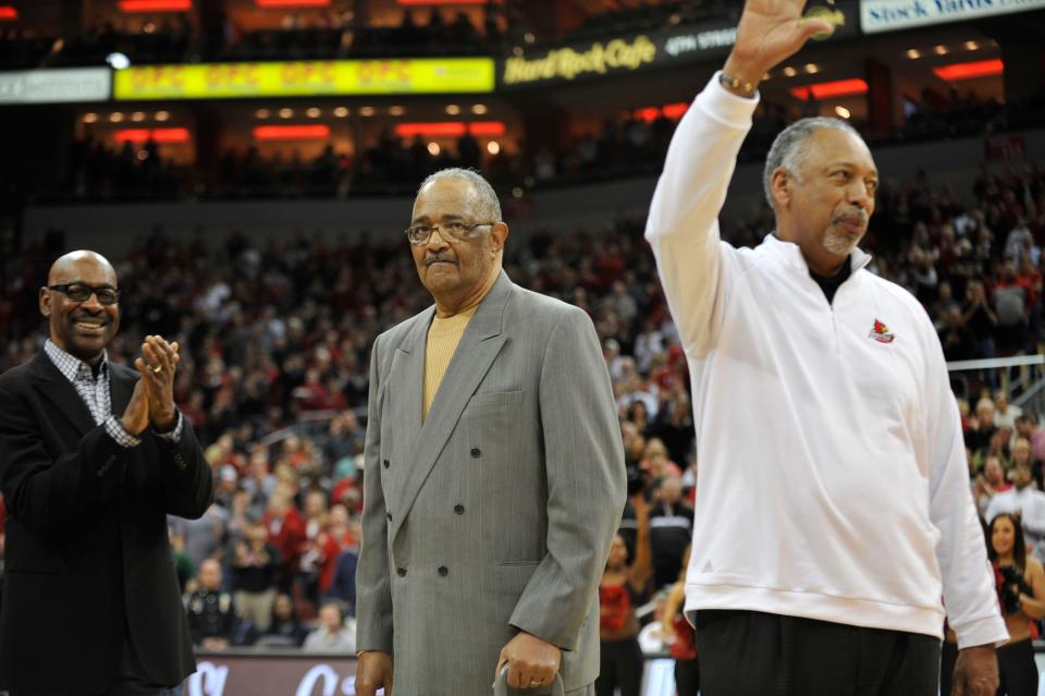 Wade Houston waves to the crowd at the KFC Yum! Center during a February 2014  Louisville men's basketball game while Eddie Whitehead, left, and Sam Smith look on. The three men were the first African Americans to play for U of L in 1962.