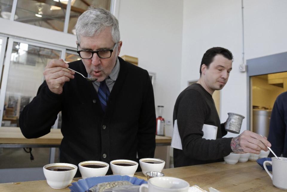 In this photo taken Thursday, Jan. 3, 2013, James Freeman, left, founder of Blue Bottle Coffee cups coffee samples, observing the tastes and aromas of brewed coffee from Uganda at his roastery in Oakland, Calif. (AP Photo/Eric Risberg)