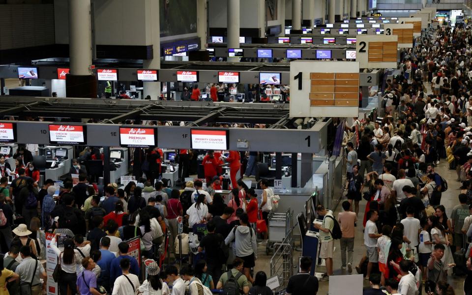 Air Asia passengers queue at counters inside Don Mueang International Airport in Bangkok