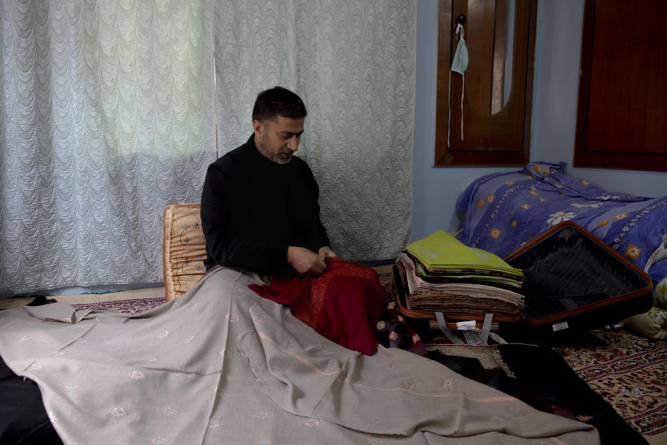 Abdul Later Allie, a Kashmiri artisan, checks the quality of pashmina shawls inside his home in Srinagar, Indian controlled Kashmir, Saturday, June 13, 2020. A months-long military standoff between India and China has taken a dire toll on local communities as tens of thousands of Himalayan goat kids die because they couldn't reach traditional winter grazing lands, officials and residents said. Nomads have roamed these lands atop the roof of the world for centuries, herding the famed and hardy goats that produce the ultra-soft wool known as Pashmina, the finest of cashmeres. Cashmere takes its name from the disputed Kashmir valley, where artisans weave the wool into fine yarn and exquisite shawls that cost up to $1,000 apiece in world fashion capitals in a major handicraft export industry that employs thousands. (AP Photo/Dar Yasin)