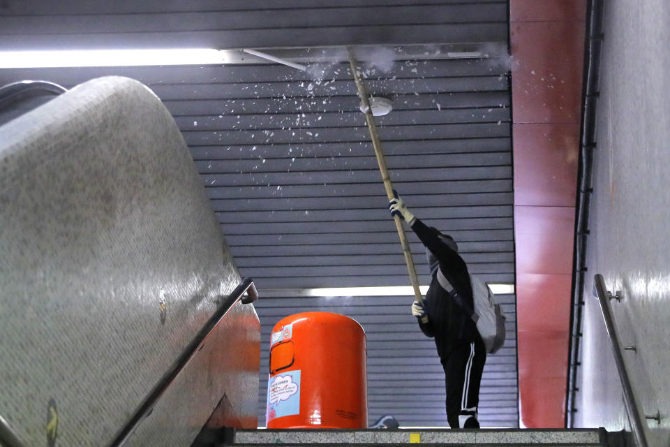 A protester destroys lighting at train station entrance during a protest in Mong Kok, Hong Kong on Friday, Sept. 6, 2019. The ratings agency Fitch on Friday cut Hong Kong's credit rating and warned that conflict with anti-government protesters was hurting the image of its business climate. (AP Photo/Kin Cheung)