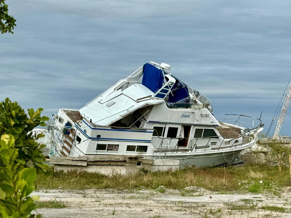 An abandoned boat lies tilted on the land next to the Caloosahatchee after Hurricane Ian dumped it there. Five women, neighbors at High Point Place, are tackling the project, asking the city of Fort Myers to clean up.