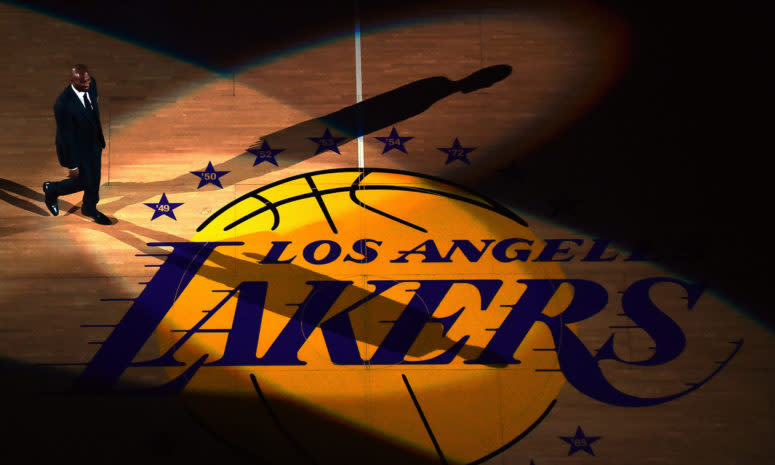 Kobe Bryant wearing a suit while standing at center court of the Staples center.