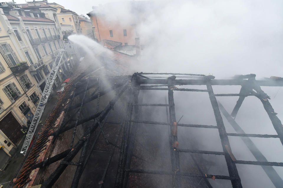 Firefighters put out a fire on the rooftop of the Cavallerizza Reale, in Turin, northern Italy, Monday, Oct. 21, 2019. A big fire broke out on Monday at Turin's Cavallerizza Reale, a historic building in the centre of the northern city which has UNESCO World Heritage status thanks to its special architectural features, no injuries were reported. (Alessandro Di Marco/ANSA via AP)