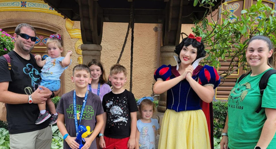 Family of seven pose with actor dressed as Snow White.