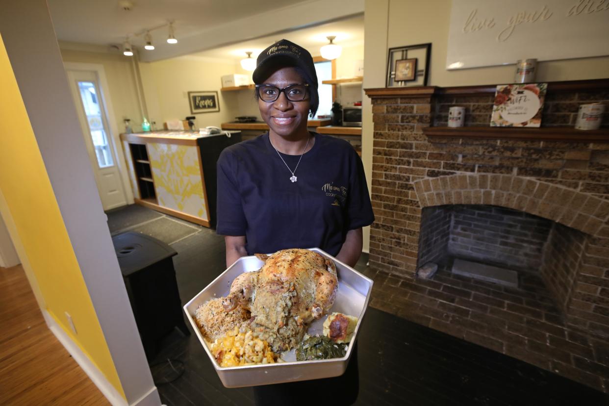Aretha McLamore holds a tray of Thanksgiving dinner at Ma'ama Tee's Cookin' & Catering on Lake Avenue in Rochester.