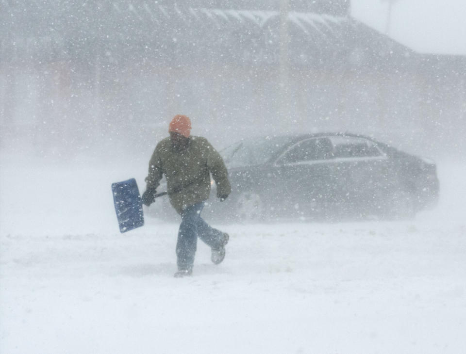 A man carrying a snow shovel walks along Market Street in Champaign, Ill., on Sunday, Jan. 5, 2014. Icy, snow-covered roads and high winds made travel treacherous from the Dakotas and Michigan to Missouri as much of the nation braced for the next winter wallop: a dangerous cold that could break records. (AP Photo/The News-Gazette, Holly Hart) MANDATORY CREDIT