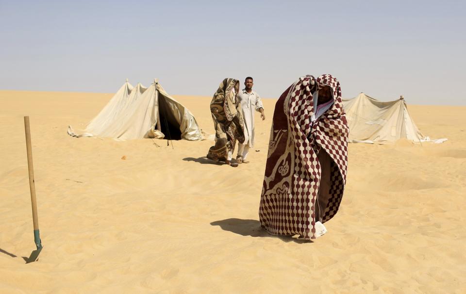 A worker helps patients, who are wrappd in a blanket, leave a "sauna" tent after their sand baths in Siwa, Egypt, August 12, 2015. (REUTERS/Asmaa Waguih)