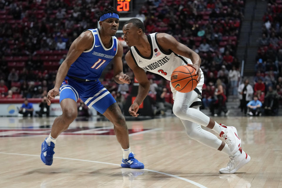 San Diego State guard Micah Parrish (3) drives with the ball as Boise State guard Chibuzo Agbo defends during the first half of an NCAA college basketball game Friday, Feb. 3, 2023, in San Diego. (AP Photo/Gregory Bull)