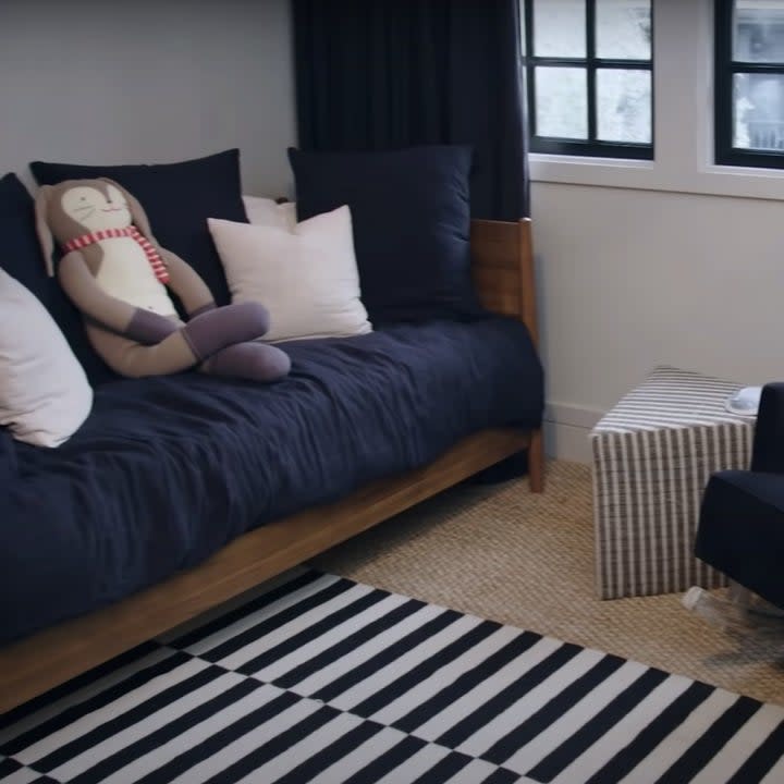 A daybed next to a velvet rocking chair on top of a black and white striped carpet