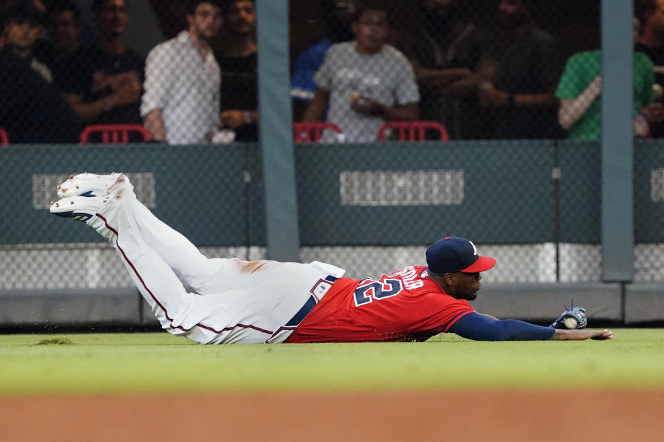 Atlanta Braves right fielder Jorge Soler (12) makes a diving catch on a fly ball by Washington Nationals' Gerardo Parra in the fourth inning of a baseball game Friday, Aug. 6, 2021, in Atlanta. (AP Photo/John Bazemore)