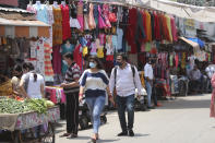 Indian commuters wear masks and walk at a market in Jammu, India, Sunday, June 7, 2020. India whose coronavirus caseload is fifth highest in the world has partially restored trains and domestic flights and allowed reopening of shops and manufacturing. (AP Photo/Channi Anand)