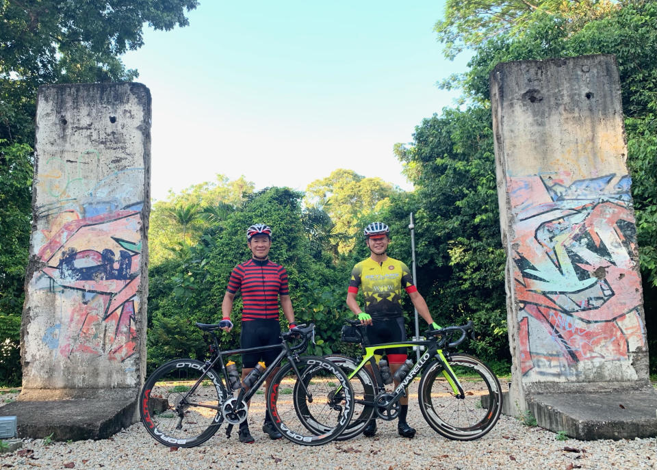 Berlin Wall Image: (from left) Dr Siong is with Bike Guru. Like many cyclists, the duo enjoys cycling to explore different parts of Singapore. They are seen here at the remnants of the Berlin Wall that divided East and West Berlin from 1961 to 1989. Located in NUS, the walls were a gift from Germany to the Singapore Ministry of Foreign Affairs in 2016, marking 50 years of diplomatic relations between Germany and Singapore. [PHOTO by Bike Guru]