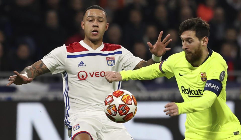 Lyon forward Memphis Depay, left, challenges Barcelona forward Lionel Messi, right, during the Champions League round of 16 first leg soccer match between Lyon and FC Barcelona in Decines, near Lyon, central France, Tuesday, Feb. 19, 2019. (AP Photo/Laurent Cipriani)