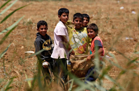 Syrian refugee boys hold a bag at a camp for Syrian refugees near the town of Qab Elias, in Lebanon's Bekaa Valley, August 8, 2017. REUTERS/Jamal Saidi