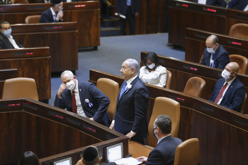 Israeli Prime Minister Benjamin Netanyahu, center, and Defense Minister Benny Gantz, center left, and other lawmakers attend the swearing-in ceremony for Israel's 24th government, at the Knesset, or parliament, in Jerusalem, Tuesday, April 6, 2021. The ceremony took place shortly after the country's president asked Netanyahu to form a new majority coalition, a difficult task given the deep divisions in the fragmented parliament. (Alex Kolomoisky/Pool via AP)