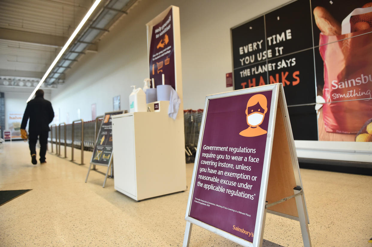 NEWCASTLE-UNDER-LYME, ENGLAND - JANUARY 12: A man walks past a face covering sign while shopping in Sainsburys on January 12, 2021 in Newcastle-Under-Lyme, England. In response to government ministers voicing concerns about the public's behaviour in supermarkets, Sainsbury's and Morrisons have both announced they will be enforcing rules on mask-wearing in their stores. The daily admissions to hospitals of coronavirus cases  has topped 4000 and the current number of patients in hospital with the virus is 32,294. (Photo by Nathan Stirk/Getty Images)