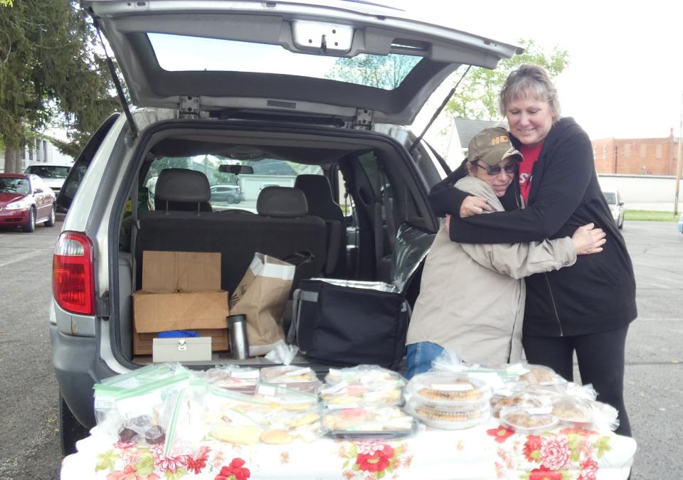 Cousins Donna Craven, left, and Connie Roub share a hug during the Dutchtown Farmers Market in New Washington on Thursday. Both are vendors at the weekly market.