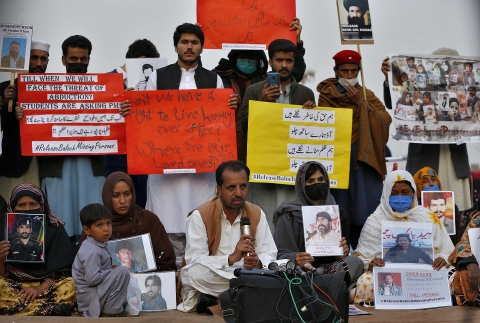 Nasrullah Baluch, center bottom, leader of the Voice of Baluch Missing Persons, speaks while people hold placards and portraits of their missing family members during a press conference in Islamabad, Pakistan, Saturday, Feb. 20, 2021. Dozens of relatives of Baluch missing persons, allegedly taken away by security agencies from restive Baluchistan province, Saturday ended their ten-day protest sleeping in the February cold near Pakistan parliament in capital Islamabad as minster for Human Rights assured their demand for recovery of loved ones would be taken seriously. (AP Photo/Anjum Naveed)