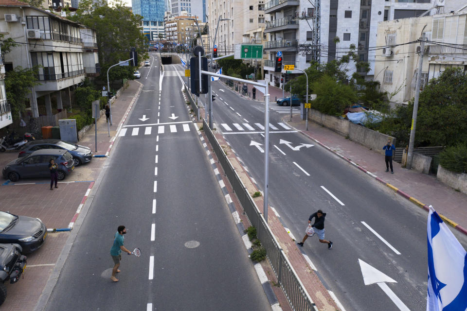 Israelis play tennis on an empty road during lockdown following the government's measures to help stop the spread of the coronavirus, in Ramat Gan, near Tel Aviv, Israel, Thursday, April 9, 2020. (AP Photo/Oded Balilty)