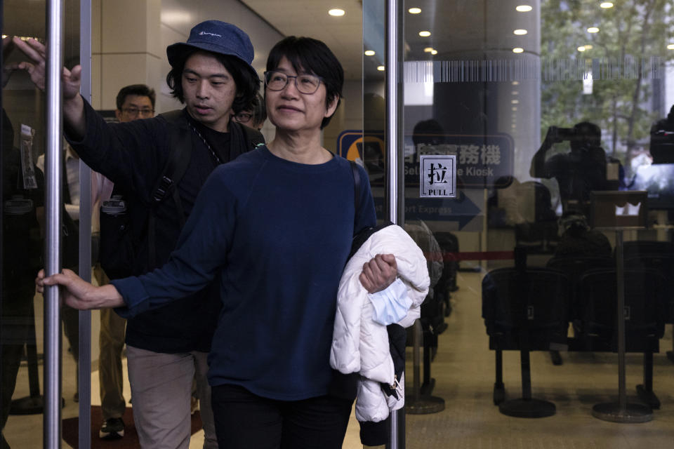 Elizabeth Tang, center, the former chief executive of the now-disbanded pro-democracy group Hong Kong Confederation of Trade Unions, walks out the police station in Hong Kong, on Saturday, March 11, 2023 Tang, who was arrested for endangering national security earlier this week, was released on bail on Saturday. Former vice-chairperson Leo Tang, is behind her. (AP Photo/Louise Delmotte)