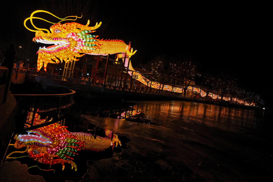 Visitors tour underneath a giant dragon lantern reflected on the frozen Houhai Lake in Beijing, Thursday, Feb. 8, 2024. Chinese will celebrate Lunar New Year on Feb. 10 this year which marks the Year of the dragon on the Chinese zodiac. (AP Photo/Andy Wong)