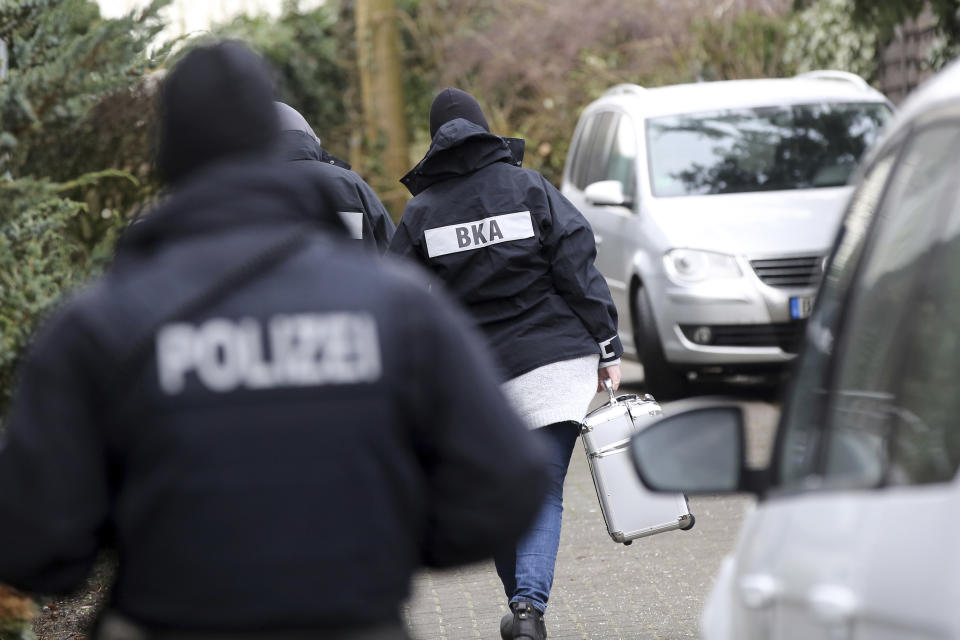 Police officer walk between cars during a raid in the village Meldorf, Germany, Jan. 30, 2019. German authorities arrested three suspected Islamic extremist Iraqi men in the norther German costal region, on allegations they were planning a bombing. (Bodo Marks/dpa via AP)
