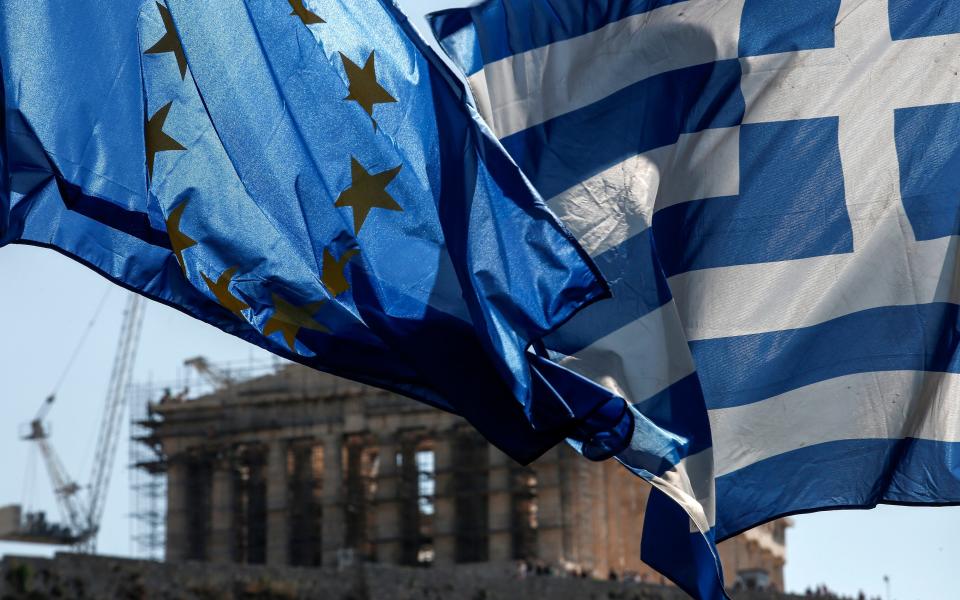 A European Union flag, left, flies beside a Greek national flag in front of the Parthenon temple on Acropolis Hill in Athens, Greece - © 2015 Bloomberg Finance LP