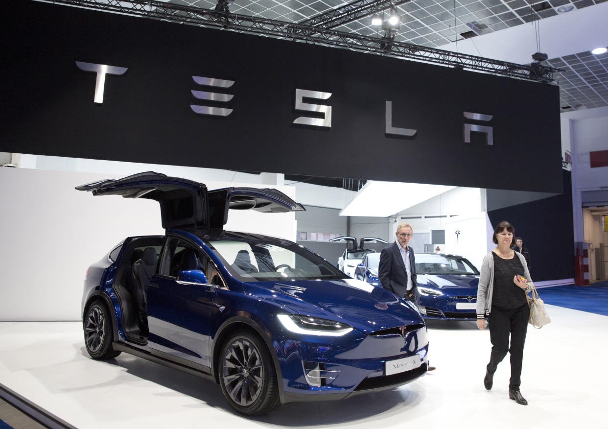 A couple walk next to the new Tesla Model X during the opening of the Brussels Auto Show in Brussels, Friday, Jan. 18, 2019. (AP Photo/Virginia Mayo)