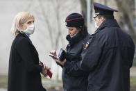 FILE - In this April 8, 2020, file photo, police officers check documents of a woman to ensure she is complying with a self-isolation regime due to the coronavirus in Moscow, Russia. A smartphone app designed to track Moscow's quarantined patients was rolled out by city officials in early April, but complaints about it have mushroomed, with users saying the software is full of glitches and has imposed unwarranted fines on them. (AP Photo/Pavel Golovkin)