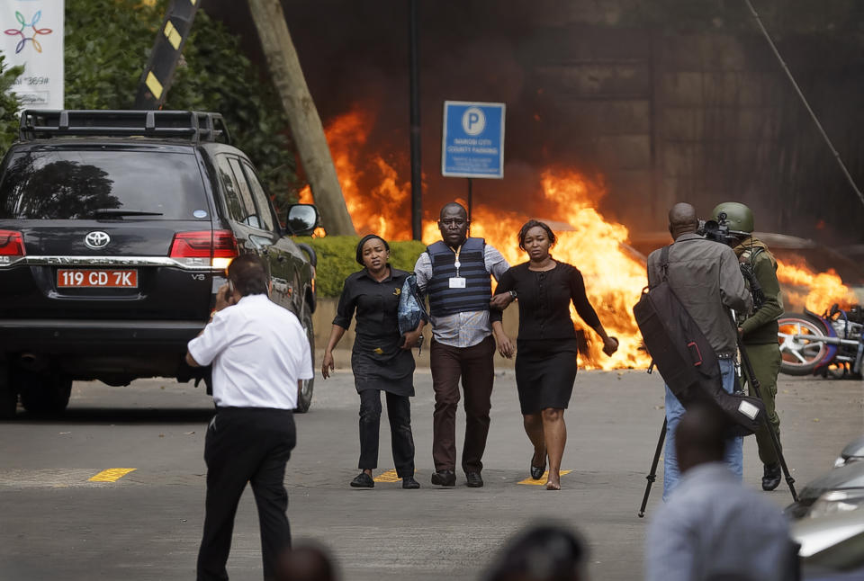 FILE - In this Tuesday, Jan. 15, 2019 file photo, security forces help civilians flee the scene as cars burn behind, at a luxury hotel complex attacked by the al-Shabab extremist group in Nairobi, Kenya. U.N. experts said in a report circulated Tuesday, Nov. 12, 2019 that al-Shabab extremists in Somalia remain "a potent threat" to regional peace and are manufacturing home-made explosives, expanding their revenue sources and infiltrating government institutions. (AP Photo/Ben Curtis, File)