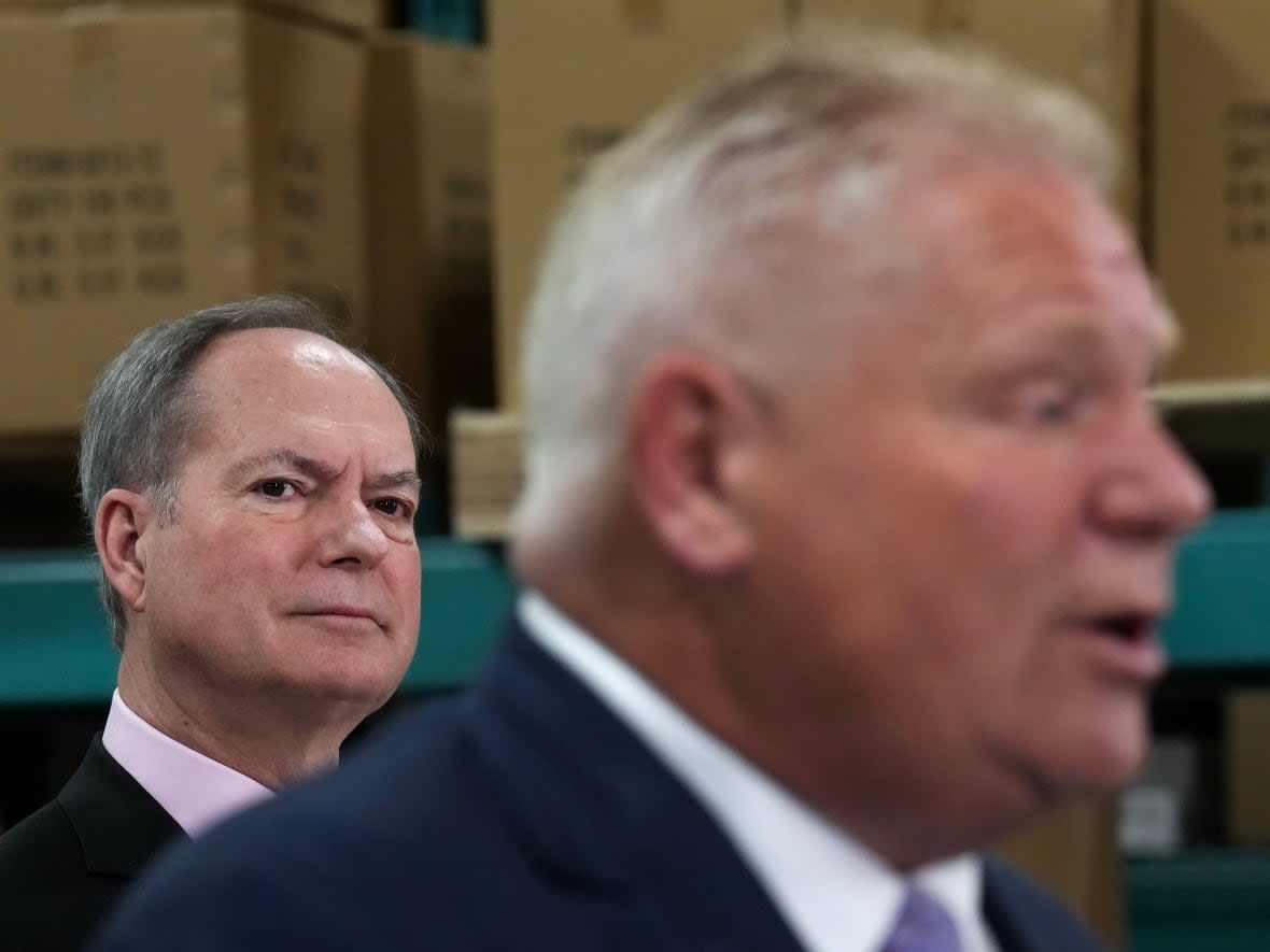 Ontario Finance Minister Peter Bethlenfalvy, left, listens to Premier Doug Ford speak during a pre-budget announcement in Oakville, Ont., on March 22. (Nathan Denette/The Canadian Press - image credit)