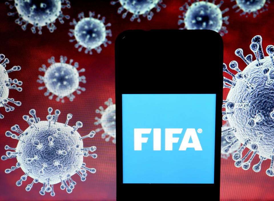 KOLKATA, INDIA - 2020/03/25: In this photo illustration a Fédération Internationale de Football Association (FIFA) logo seen displayed on a smartphone with a computer model of the COVID-19 coronavirus the background. (Photo Illustration by Avishek Das/SOPA Images/LightRocket via Getty Images)