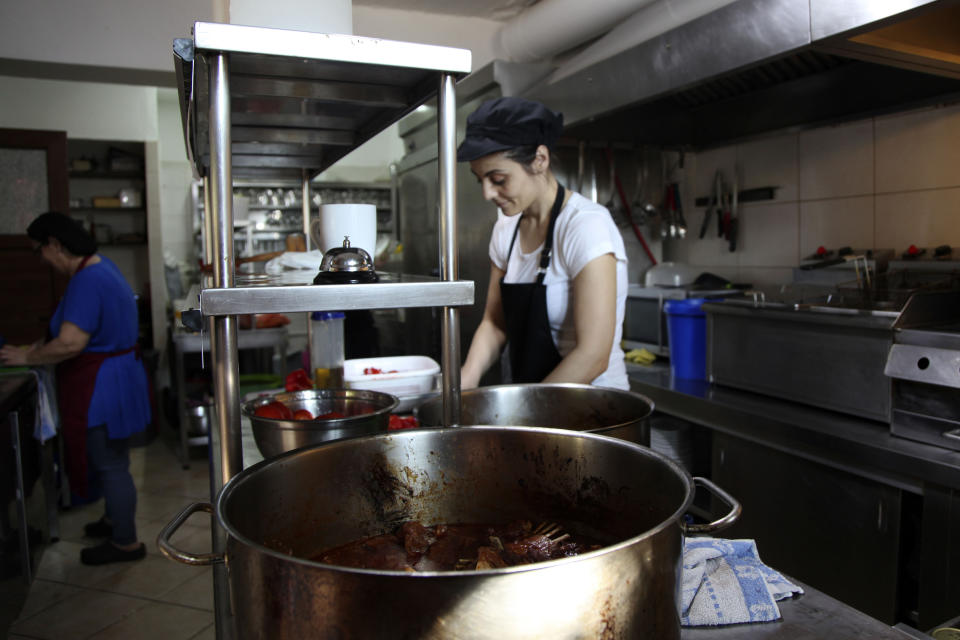 In this Sept. 8, 2019, photo, the chef Polixeni prepares goat dishes in Ano Meria village, Samothraki island, northeastern Greece. Goat herding is a way of life on Samothraki, a hard-to-reach Greek island in the northern Aegean Sea, but experts and locals are working together to control the animal population that has left its mountains barren and islanders under the threat of mudslides. (AP Photo/Iliana Mier)